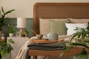 Mesa de noche con taza y objetos personales junto a una cama
