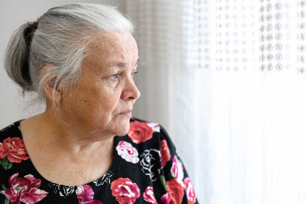 Primer plano de una mujer adulta mayor mirando por una ventana