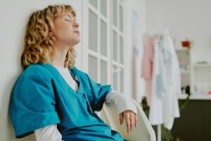 Profesional de enfermería agotada descansando junto a una ventana