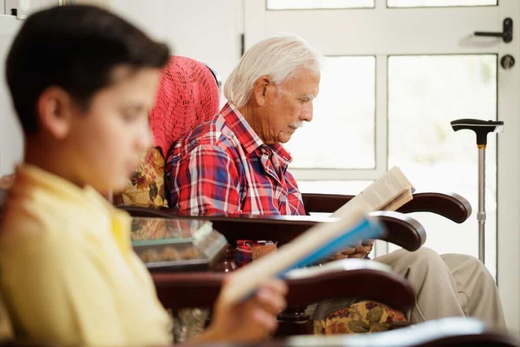 Adulto mayor y joven leyendo juntos en casa