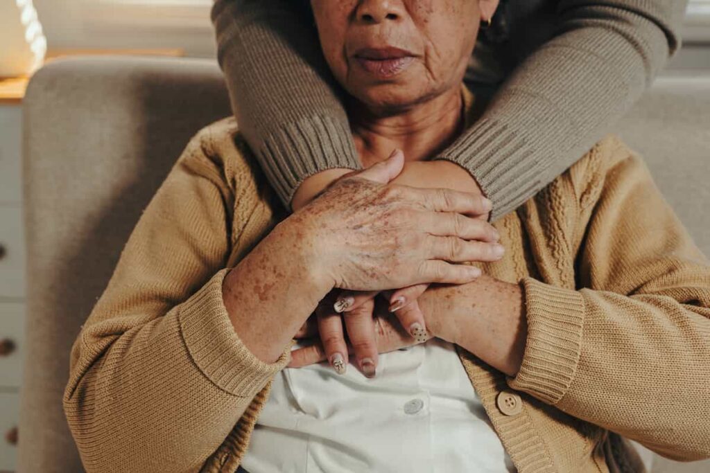 Cuidador consolando a una mujer adulta mayor con una mano en el hombro