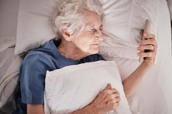 top-view-senior-woman-and-phone-on-bed-in-bedroom-2026-01-09-09-40-20-utc